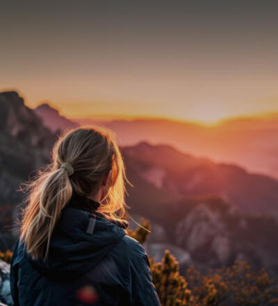Eine Frau schaut in den Sonnenuntergang in den Bergen